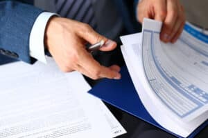 Man’s hands, rifling through a stack of business papers in NY