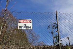 "No Trespassing" sign on a tall fence