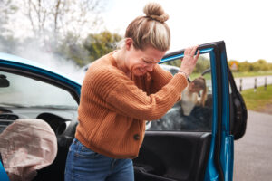 Woman getting out of a smoking car after a motor vehicle accident, perhaps a third-party fault